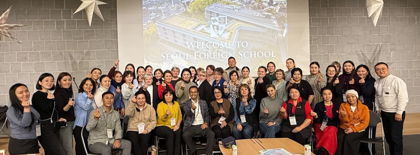 A large group photograph in front of a “Welcome to Seoul Foreign School” slide.
